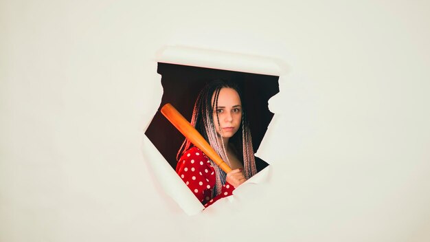 young woman with baseball bat in hole of white background pretty lady with bat
