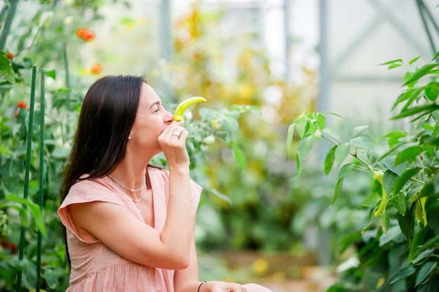 緑と野菜の温室でのバスケットを持つ若い女性。収穫時期