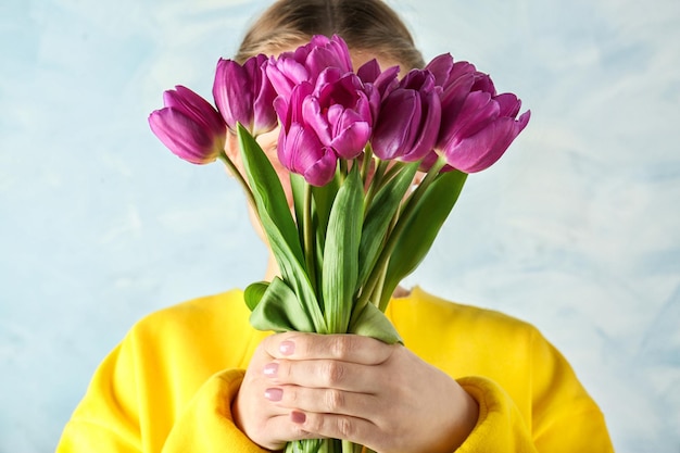 Young woman with beautiful bouquet of lilac tulips closeup