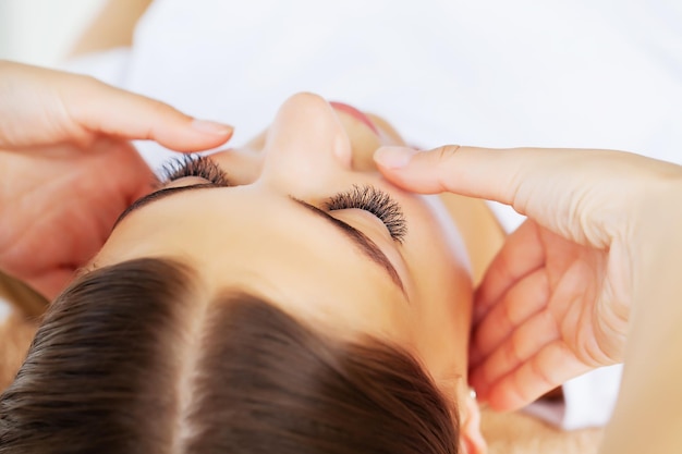 Young woman with beautiful face on facial massage in beauty studio.