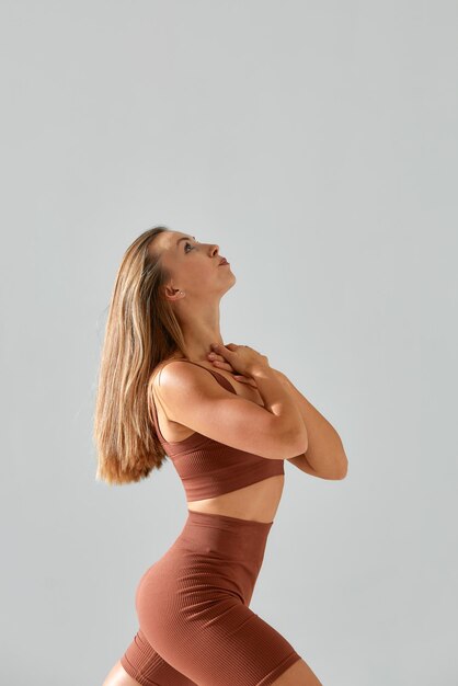 Молодая женщина с красивым стройным здоровым телом позирует в студии Фитнес-модель в спортивной одежде на сером фоне