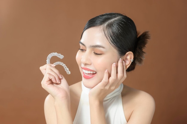 A young woman with beautiful teeth is holding Invisalign healthy dental concept