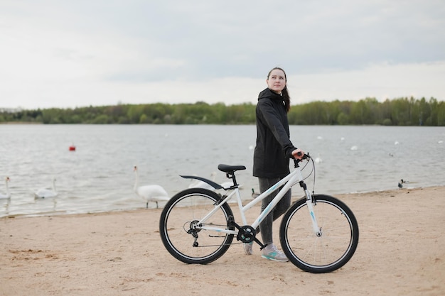 Молодая женщина с велосипедом на озере