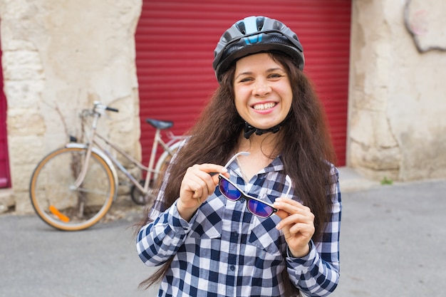 背景の赤いドアに自転車探しカメラを持つ若い女性