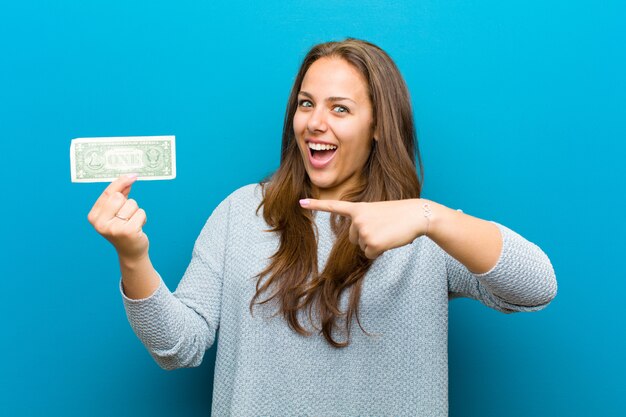 Young woman with bills against blue 