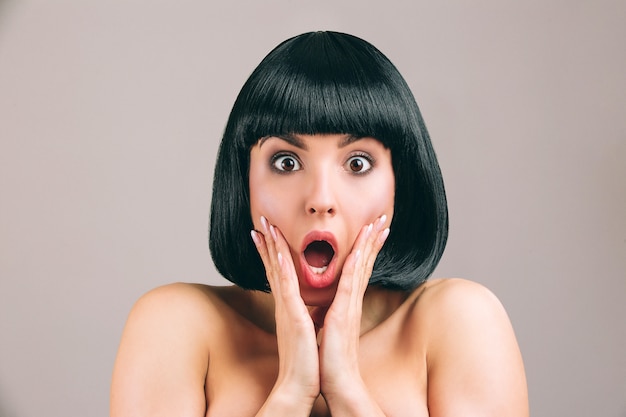 Young woman with black hair posing. Amazed scared brunette with bob haircut look straight.