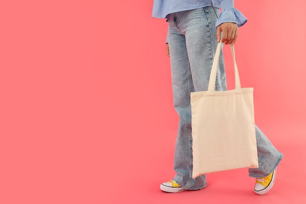 Young woman with blank cotton bag on pink background