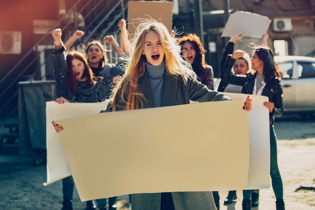 Фото Молодая женщина с пустым плакатом перед людьми, протестующими против прав женщин