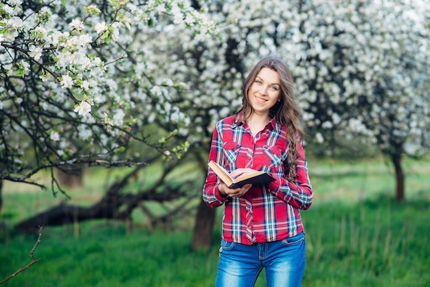 Giovane donna con il libro in un giardino fiorito