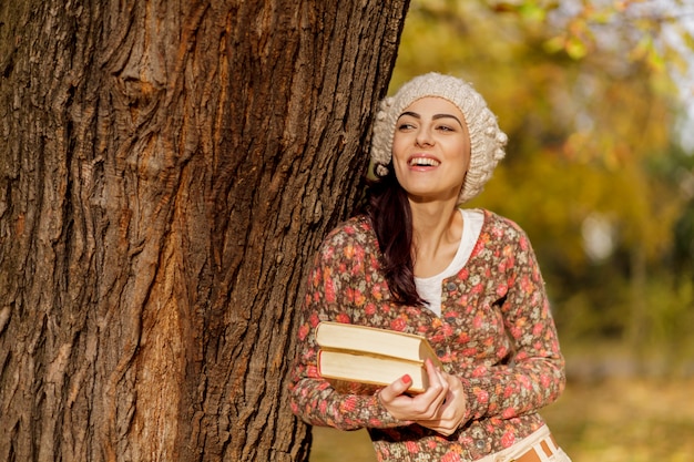 Young woman with books at the autumn forest