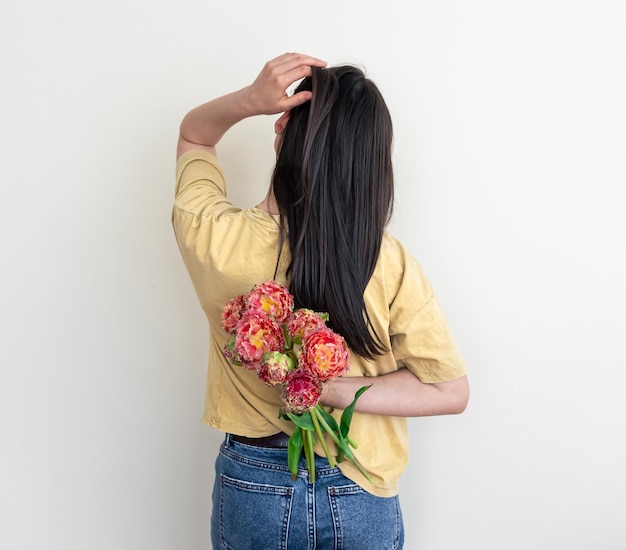 白い背景に花の花束を持つ若い女性