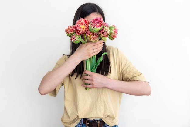 白い背景に花の花束を持つ若い女性