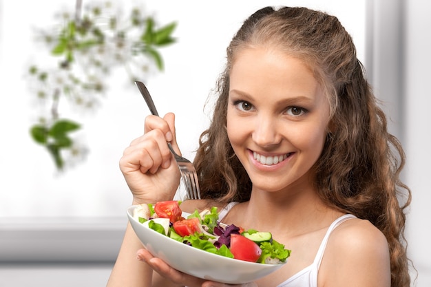 Giovane donna con una ciotola di insalata su sfondo di cibo sano