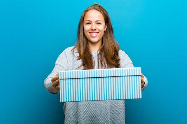 Young woman with a box against blue background