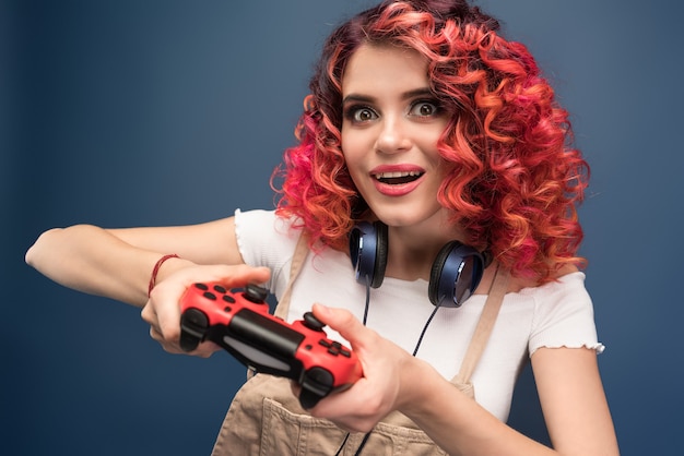 밝은 빨간색 cyrly 머리 비디오 게임을 가진 젊은 여자.