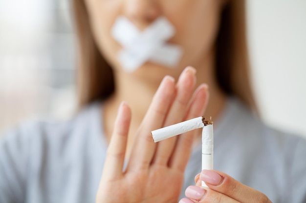 壊れたタバコを持つ若い女性、喫煙の概念を停止します。