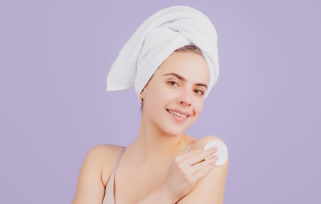 Young woman with calm face enjoys bath procedures wrapped towel on head isolated on studio backgroun