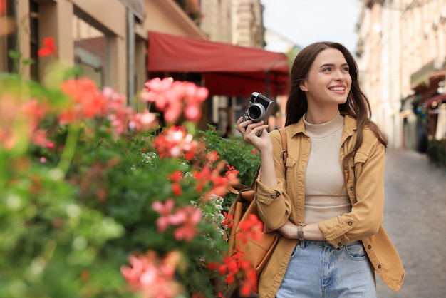 Young woman with camera on city street Interesting hobby