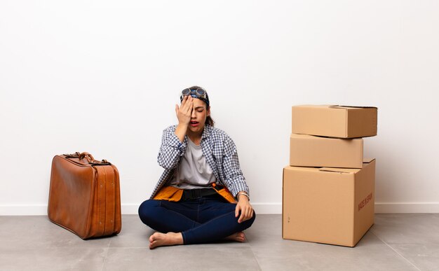 Young woman with cardboard boxes and suitcase. Moving concept