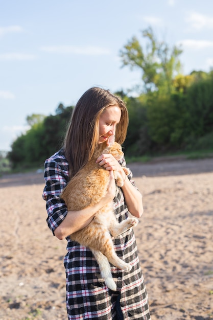 Молодая женщина с кошкой на пляже