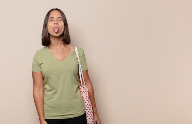 Young woman with cheerful, carefree, rebellious attitude, joking and sticking tongue out, having fun