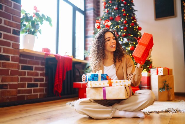 Photo young woman with christmas gifts at home near christmas tree winter holidays new years