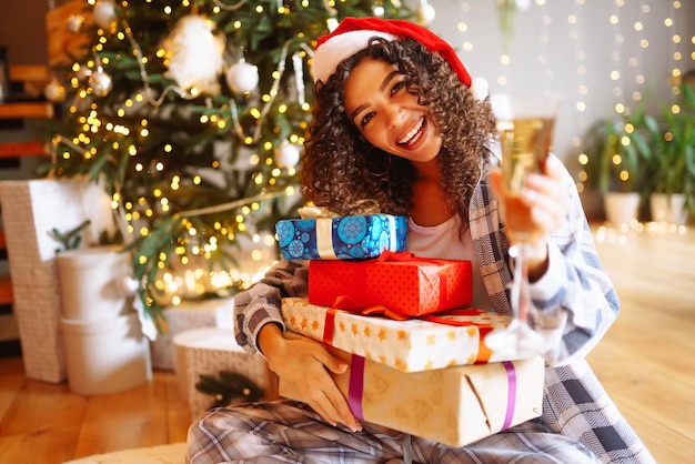 クリスマス ツリーの近くの家でクリスマス プレゼントを持つ若い女性冬の休日正月