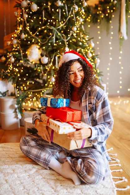 クリスマス ツリーの近くの家でクリスマス プレゼントを持つ若い女性冬の休日正月