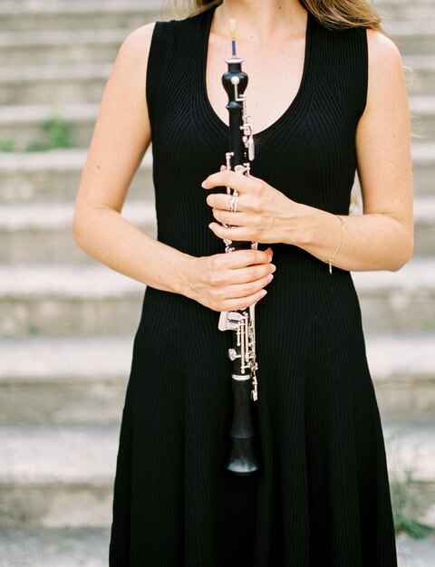 Foto una giovane donna con un clarinetto in mano si trova sui gradini di un antico edificio ritagliato senza volto