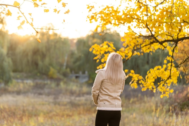 손을 꼭 잡고 기도하는 젊은 여성, 가을에는 자연 속에 서 있다