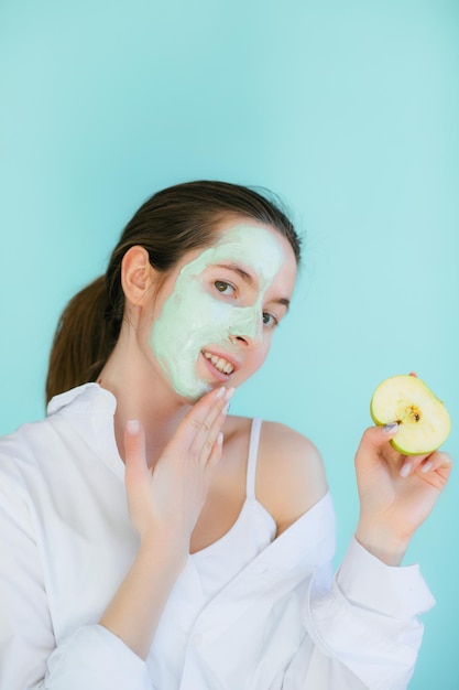 Young woman with clay mask on her face against light background, space for text. Skin care