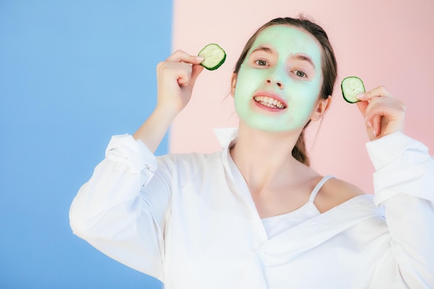 Young woman with clay mask on her face against light background, space for text. Skin care