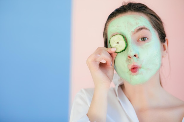 Young woman with clay mask on her face against light
background, space for text. skin care