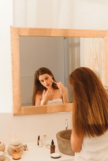 Young woman with clean beautiful skin makes massage with a jade roller for the face Home spa Skin care