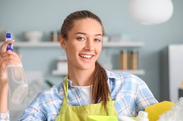 Photo young woman with cleaning supplies in kitchen