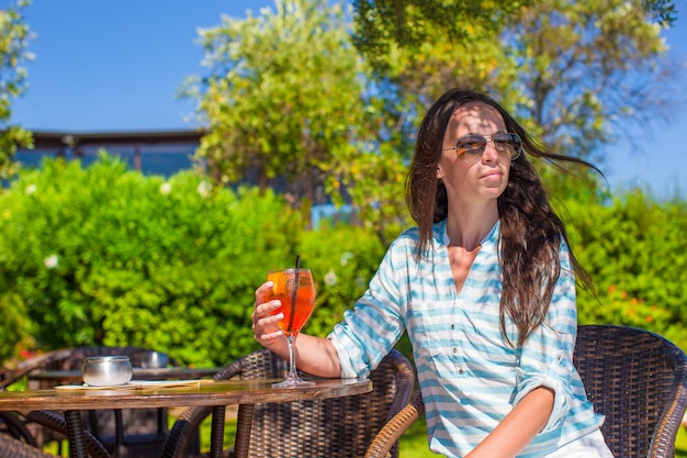 Young woman with cocktail in tropical cafe at exotic resort