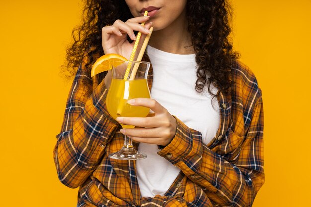 Foto giovane donna con cocktail su sfondo giallo