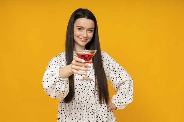 Young woman with a cocktail on a yellow background