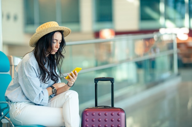 Young woman with coffee in an airport lounge waiting for flight aircraft