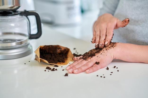 Young woman with coffee grounds use it for peeling