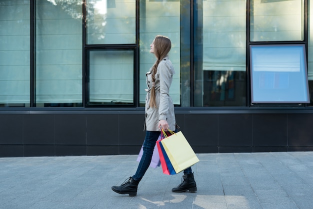 通りを歩いてカラフルなバッグを持つ若い女性。