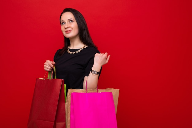 A young woman with colorful shopping bags on a red background