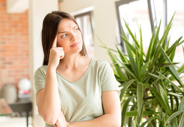 Young woman with a concentrated look wondering with a doubtful expression looking up and to the side