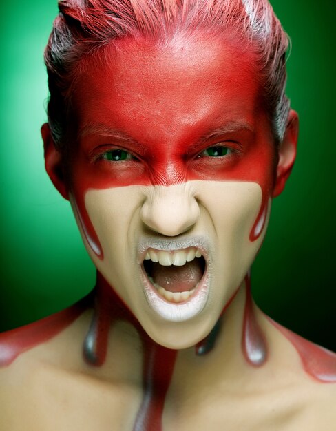 Young woman with creative face-art over green background