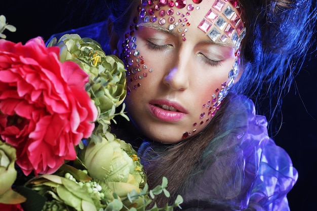 Young woman with creative make up holding flowers