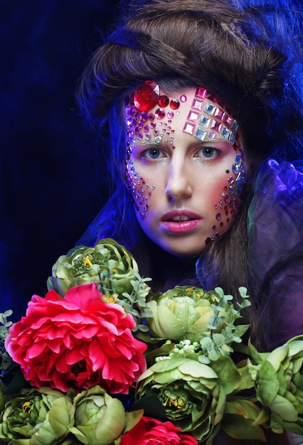 Young woman with creative make up holding flowers