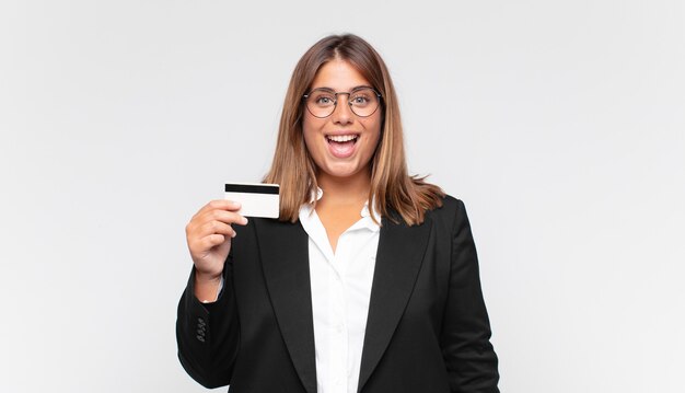 Young woman with a credit card looking happy and pleasantly surprised