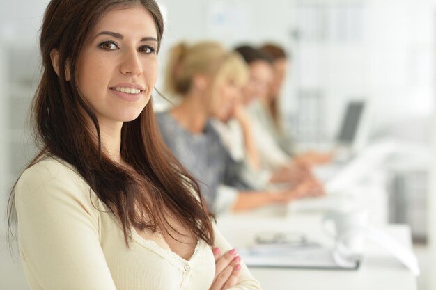 Young woman with crossed arms colleagues on background