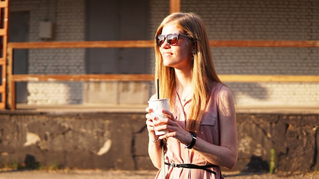 Young woman with a cup of lemonade outside sunny day and urban food court