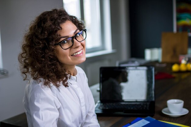 young woman with curly hair in business attire in the office